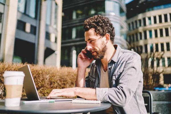 Poważny Mężczyzna Freelancer Pracuje Zdalnie Tarasie Kawiarni Rozmawiając Przez Telefon — Zdjęcie stockowe