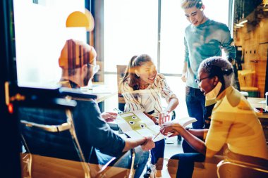 Başarılı bir başlangıç stratejisi geliştirmekten memnun olan neşeli erkek ve bayan meslektaşlar takım halinde işbirliği yapıyor, çok ırklı öğrencilerden oluşan mutlu bir ekip atölye çalışmasından keyif alıyor.