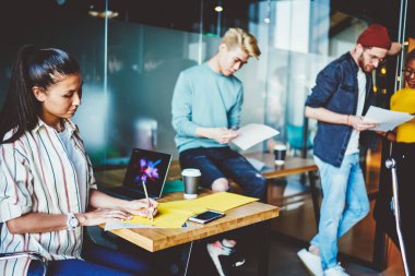 Modern sınıftaki dersler sırasında gündelik giysiler giymiş çok kültürlü öğrenciler. Ofiste birlikte tasarım çizimleri çizen düşünceli genç insanlar.