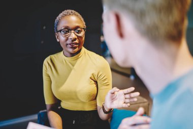 Afrika kökenli Amerikalı bir kadının göz jesti görüntüsü erkek meslektaşına bilgi verirken, çok ırklı çalışanların iş ortaklığı projesiyle ilgili konuşması