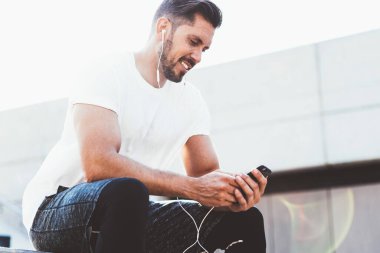Beyaz erkek koşucu şık spor kıyafetleri giyip Wright kardiyo eğitimini yayınlıyor. Modern akıllı telefon zımbırtısıyla internete bağlı, mutlu adam sesli mesaj dinliyor.