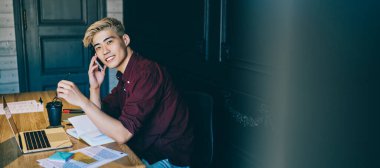 Başarılı Çinli hipster IT geliştiricisinin portresi internet üzerinden akıllı telefondan arama yaparken internet üzerinden kablosuz internet kullanıyor. Cep telefonuyla konuşan pozitif Japon genç adam.