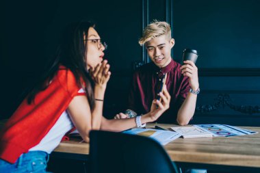 Modern çalışma ortamında kahve molası sırasında akıllı telefon cihazıyla fotoğraf çeken Çinli arkadaşlar. Masaüstünde oturan cep telefonlarında ücretsiz 4G internet bağlantısı kullanan neşeli Japon öğrenciler.