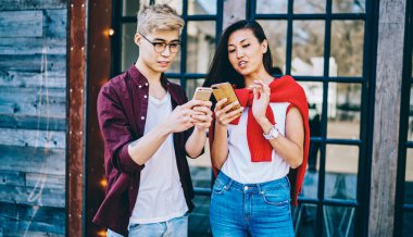 Gündelik giyinmiş Çinli yenilikçi blogcular, şehir ortamında 4G internet bağlantısı kullanarak akıllı telefondan mobil uygulamayı tartışıyor. Ellerinde selüler olan iki Asyalı arkadaş sosyal ağdan bahsediyorlar.