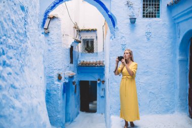 Renkli şehirde profesyonel kameralı güzel bir kadın fotoğraf çekiyor - Fas 'ta yeni ekipmanlar test ediliyor, kadın fotoğrafçı tatillerde eski sokakların fotoğraflarını çekiyor