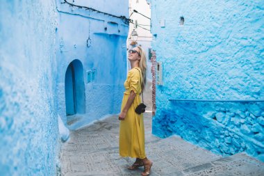 Omzunda retro teknolojisi olan çekici bir kadın gazeteci Fas 'ın eski berber mimarisinin nefes kesici manzarasının tadını çıkarıyor, güzel pozitif kadın turist Chaouen Medina' yı keşfediyor.
