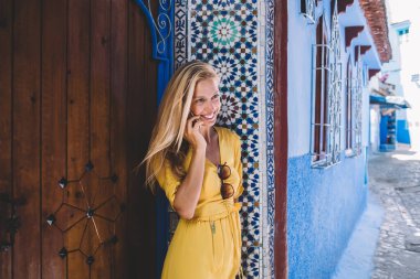 Uluslararası sohbet için cep telefonu cihazını kullanan neşeli bayan turist Chaouen 'deki fresk binasının yanında duruyor, neşeli hippi kız çevrimiçi sohbetten keyif alan gezgin kızdan çağrı alıyor.