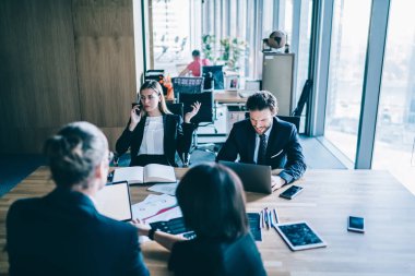 Şirket için strateji planı üzerinde çalışan iş arkadaşlarıyla birlikte masaüstünde otururken operatörden önemli bir telefon alırken internet bağlantısı kullanan ciddi bir kadın yönetmen.