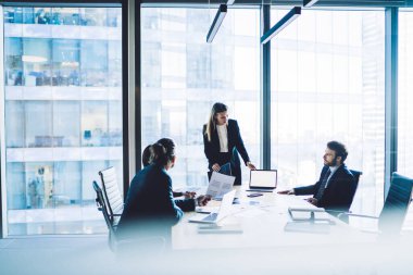 İşbirliği ve konferans odasında yapılan beyin fırtınası sırasında dizüstü bilgisayardaki finansal metnin reklamını yapmak için kendine güvenen kadın patron, girişimcilik kavramı.