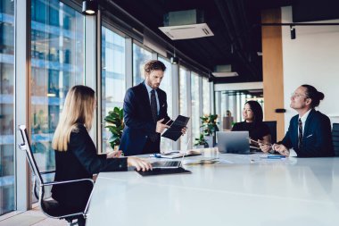 Profesyonel çalışanların toplantı saatleri şirket şirketinin konferans odasında, akıllı erkek ve bayan meslektaşlar resmi olarak giyinmiş sözleşme ve yatırım detayları için bilgi tartışıyorlar.