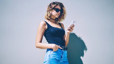 İletişim kurmak için mobil uygulama üzerinden arkadaşlarıyla video görüşmesi yapan bir kadın, promosyon arka planının yanında dururken, hippi kız internet taraması için akıllı telefon aygıtı kullanıyor.