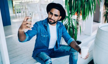 Milenyum yakışıklısı elinde kafein içeceği ve selfie fotoğraflarıyla paket servis bardağı tutan adam, Türk erkek blogcu moda sayfasında içerik yayını yarattığı için kendisini fotoğraflıyor