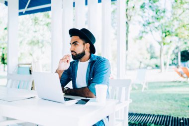 Düşünceli erkek serbest çalışan, verileri ve medya dosyalarını korumak için modern laptop aygıtı için daha iyi bir antivirüs programı üzerinde kafa yoruyor.