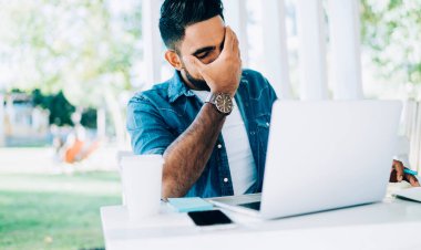 Program kodlarıyla uzaktan çalışan İspanyol yazılım geliştirici teslim tarihinden yorgun hissediyor, yetenekli erkek metin yazarı modern netbook ile sokak terasında oturuyor ve çevrimiçi problemden bitap düşmüş durumda.