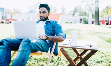 Üniversitenin kampüs bölgesinde dinlenen kaygısız hippi üniversite arkadaşlarıyla online sohbetten keyif alan, yeni web mağazaları arayan mutlu bir Türk.