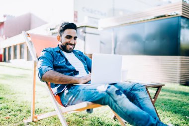 Mutlu adam, arkadaşının mesajını okurken gülümsüyor. İnternet sitesinden laptoptaki internet bağlantısı için metin içeriğini arıyor. Çevrimiçi iletişim kavramı.