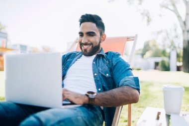 Neşeli sakallı bir adam kendi blog sayfasında yayınlamak için metin bilgileri yazıyor olumlu eleştiriler ve yorumlardan kendini iyi hissediyor, mutlu erkek serbest çalışan dizüstü bilgisayardaki internet sitelerini tarıyor.