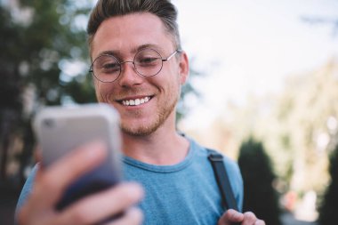 Akıllı telefon ekranına bakan neşeli Kafkasyalı hipster 'ı kapat ve cep telefonuyla internet sitelerine göz gezdiren mutlu adam, arkadaşından olumlu e-posta alınca kendini iyi hisset.