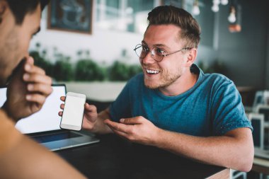 Mutlu erkek blogcuların cep telefonundan gelen komik mesajları reklam metinleri için fotokopi alanı ile tartışırken yan görünümü, web siteniz için boş ekranlı modern akıllı telefon aygıtı