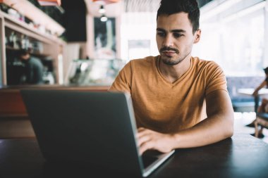 Ciddi erkek yazılım geliştirici dizüstü bilgisayarla masada oturuyor ve yeni web sitesi veritabanı için program kodu yaratıyor, genç adam internet bağlantısı kullanarak modern netbook 'ta uygulamayı test ediyor