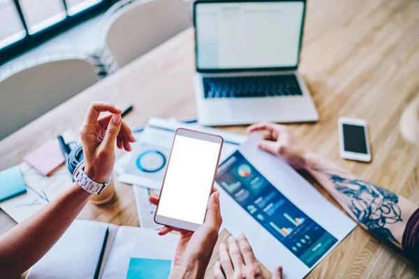İnternet içeriğiniz için boş ekran alanı olan el kameralı modern akıllı telefon görüntüsü arkaplanda tahta masaüstü ve diyagram ve dizüstü bilgisayar çizimi. Mobil cep telefonu.