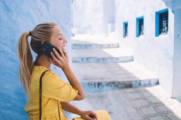 Happy woman smiling while receiving international operator cell call communicating with best friend for sharing travel impressions, cheerful female tourist talking via smartphone connect to 4g