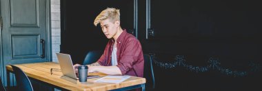 Modern uzayda kablosuz internet bağlantısı kullanarak dijital dizüstü bilgisayarda serbest çalışan düşünceli Japon genç adam. Mesafeli iş için bilgisayara uygulama yükleyen konsantre Asyalı hipster.