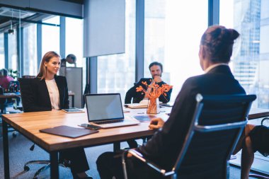 Resmi giyinmiş zeki iş adamları toplantı masasında oturup şirket ofisindeki çalışma süreci boyunca başlangıç projesiyle ilgili bilgi ve girişimcilik kavramını tartışırlar.