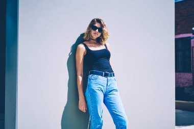 Tatillerde duvara yakın poz veren gözlüklü modaya uygun hippi kız portresi. Şehir sokaklarında yürüdükten sonra şık giyimli genç ve çekici kadın kameraya bakıyor.