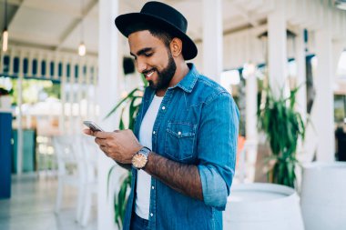 Siyah şapkalı bir Türk 'ün sosyal ağlardan en sevdiği blogcuya cep telefonuyla 4G kablosuz bağlantı kurduğu için kısa mesaj yazışının yan görüntüsü, mutlu adam arama telefonu numarası