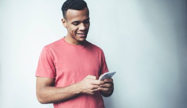 Mutlu koyu tenli adam cep telefonuyla online oyunlar oynuyor başarılı hipster adam tanıtım alanında arkadaşlarıyla mesajlaşırken akıllı telefondan e-postaları kontrol ediyor.