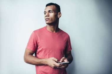 Modern hücresel cihazları elinde tutan hippi adam ve düşünceli bakışları bir yana, bin yıllık Afrikalı Amerikalı erkek blogcu cep telefonuyla sosyal ağlarda yayın yapma fikri üzerine düşünüyor.