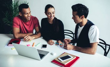 Genç, çok ırklı erkek ve kadın meslektaşların, proje stratejisi planlarken fikir alışverişinde bulunması ve fikir alışverişinde bulunması, kapalı alanlarda iş birliği yapan başarılı bir grup genç.