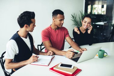 Çok ırklı iş arkadaşlarıyla yapılan beyin fırtınası sırasında internetteki web sitesi linki ile gündelik kıyafetlerle arama yapan Afrikalı Amerikalı erkek çalışanlar, başarılı bir cep telefonu araması yapan kadın.