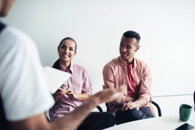 Sıradan giyinmiş neşeli beyaz kadın iş arkadaşından gelen bilginin sunumu sırasında gülümsüyor, kapalı alanda işbirliği yapan mutlu çok kültürlü insanlar, girişimcilik kavramı.