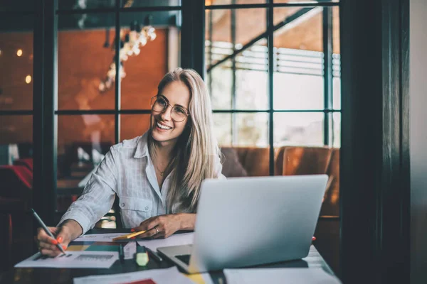 Lächelnde Lässige Blondine Mit Brille Sitzt Mit Laptop Und Papierdiagrammen — Stockfoto