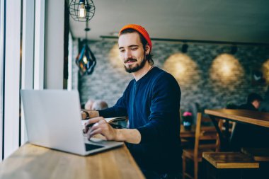 Reklam alanında uzaktan çalışan beyaz erkek haberleri kontrol ediyor. İnternet sayfasından bilgi okuyan serbest çalışan bir adam internete bağlı dizüstü bilgisayarın ekranına bakıyor.