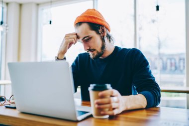 Kafkas erkek öğrenci yorgun hissediyor web sayfasında internete bağlı dizüstü bilgisayarla sıkıcı eğitim webinar izlerken, yetenekli serbest yazar web sitesinde yararlı makaleler okuyor