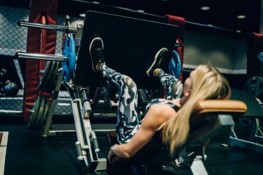 Tanımlanamayan sarışının arka plan görüntüsü kararlı sporcu kadın ve spor ayakkabıları modern spor salonunda ağırlık kaldırıyor.