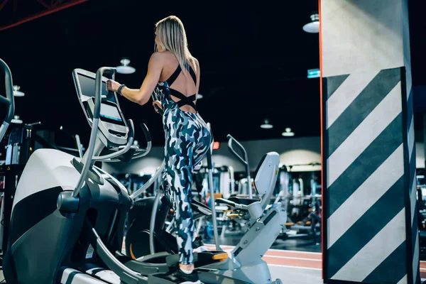 穿着时髦的现代运动服在健身房跑步机上锻炼的成年女运动员的回顾 — 图库照片