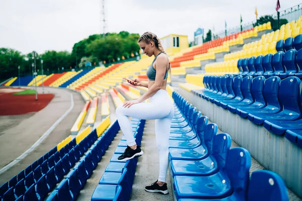 Spor Kıyafetli Atletik Sarışın Kadın Boş Stadyumun Sol Bacağı Üzerinde — Stok fotoğraf