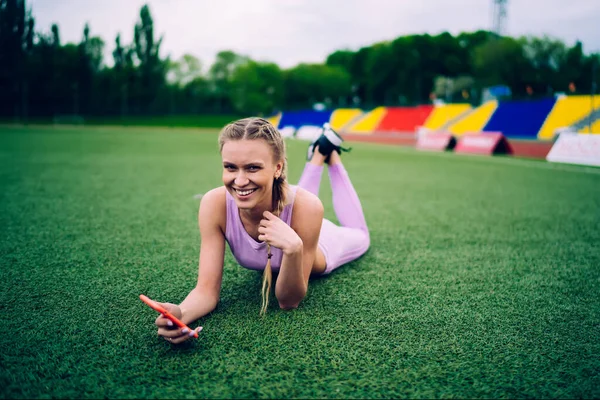 Gülen Sporcu Kadın Sahada Akıllı Telefonuyla Yatıyor — Stok fotoğraf