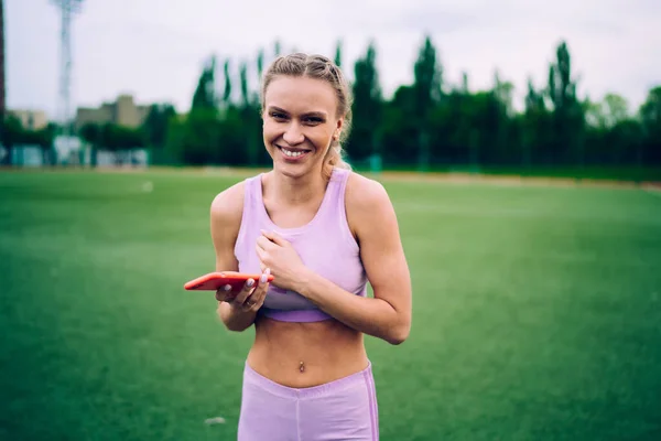 Šťastná Atletická Mladá Žena Purpurovém Sportovním Oblečení Pomocí Mobilního Telefonu — Stock fotografie