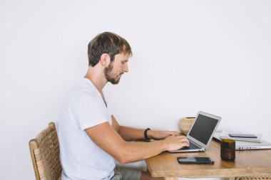 Ciddi bir erkek yazılım geliştiricisinin internete bağlanıp internete bağlanan antivirüs uygulamasını güncellemesinin yan görüntüsü, Kafkasyalı serbest yazar makaleye odaklandı