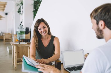 Reklam metni ya da web sitesi verileri için fotokopi alanı olan boş bir dizüstü bilgisayar, mutlu erkek ve kadın girişimciler kapalı alanlarda birlikte çalışma kitaplarından notlar tartışıyorlar.