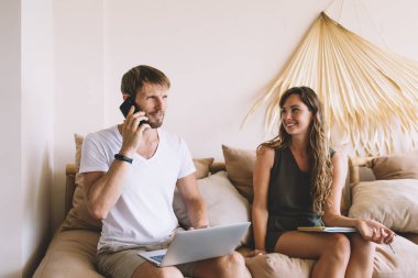 Not defterli neşeli, güzel bir kadın. Akıllı telefondan konuşan yakışıklı bir adama bakıyor. Dizüstü bilgisayarını karıştırıyor.