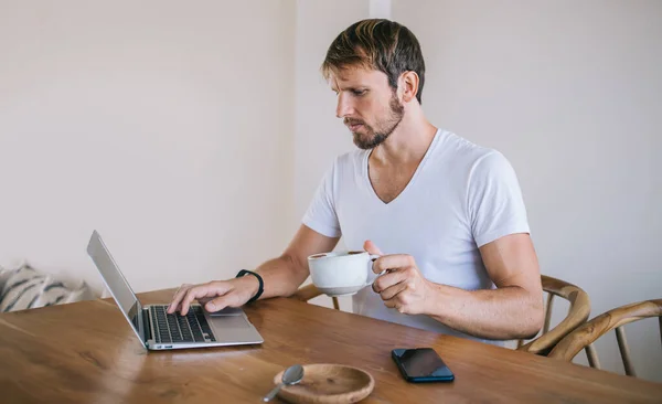 Homem Casual Focado Camiseta Branca Tomando Café Enquanto Senta Mesa — Fotografia de Stock