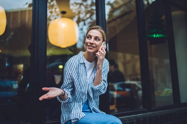 Mujer Rubia Sonriente Con Ropa Casual Sentada Cerca Ventana Gesticulando — Foto de Stock