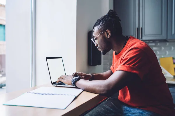 Вид Сбоку Современного Афроамериканца Очках Сидящего Прилавком Блокнотом Сидящего Ноутбуке — стоковое фото