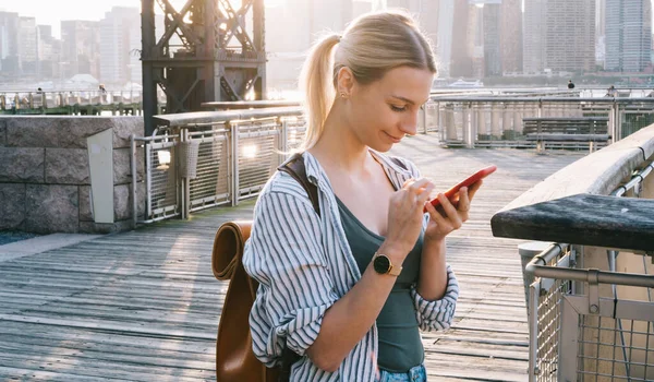 ブルックリン地区の都市部に立つ携帯電話のデバイスを介して情報を確認し 公共のアメリカのWifiインターネットに接続するためのバックパック付き正ヒップスター観光客 ブログ時間 — ストック写真